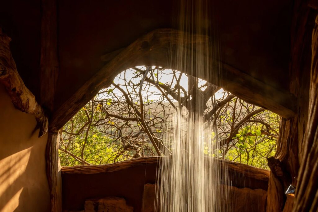 Open-air shower framed by acacia branches at Tassia Lodge