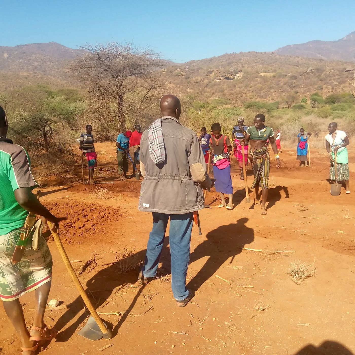 Community members walking to the Tenge Block work site with hand tools