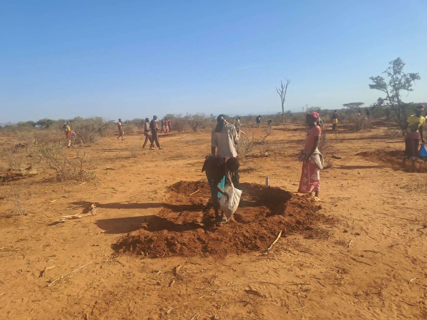 Community members shaping a semi-circular bund at Tenge Block